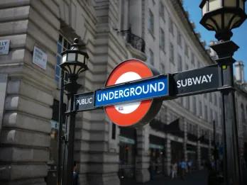 London Underground Red circle with blue line through it and white block writing saying UNDERGROUND sign. There are old lamp posts on either side.