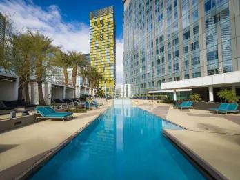 Waldorf Astoria Las Vegas Modern building with a rectangular pool and sun bed beside it. In the background there is a yellow building.