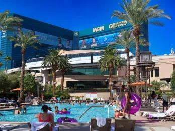A monorail wrapping around a large modern hotel right in front of the large pool.