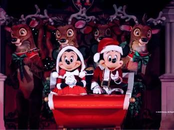 Mickey and Minnie in Santa outfits on a sleigh in front of reindeer