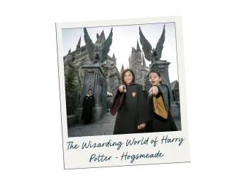 The Wizarding World of Harry Potter - Hogsmeade Two young girls in black wizard robes pointing wands towards the camera in front of the Hogwarts castle.