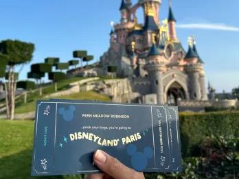 AttractionTickets.com Souvenir Tickets A souvenir ticket for Disneyland Paris held up in front of Sleeping Beauty Castle