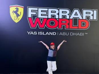 Ferrari World Yas Island, Abu Dhabi Girl stood in front of Ferrari World sign which has black background, red and white text and the Ferrari logo next to the name.