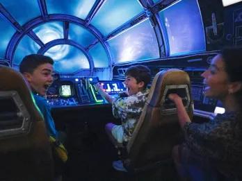 Two young boys sat in the pilot seats of the Millennium Falcon
