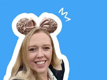 Michelle Smiling lady with long blonde hair, wearing pink mouse ears, blue background