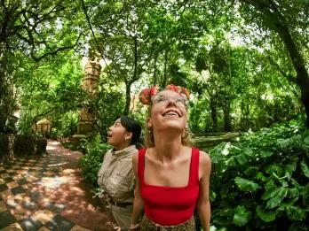 Two young women looking up into the trees while walking through a jungle trek