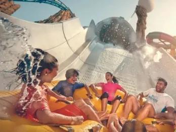 Yas Island, Abu Dhabi Four people laughing on a water slide at Yas Waterworld.