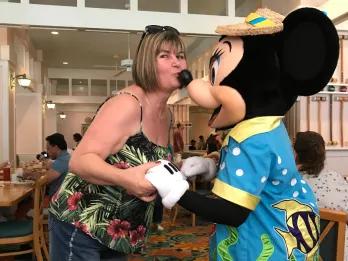 Sammie - Jump the Queue Podcast Host Sammie kissing Minnie Mouse on the nose in a character dining restaurant.