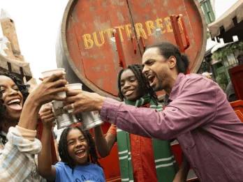 An excited family raising Butterbeer beverages in celebration, capturing an unforgettable and unique experience in The Wizarding World of Harry Potter at Universal Orlando Resort.
