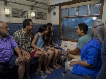 A multigenerational family riding the enclosed Hogwarts Express attraction at Universal Orlando Resort, enjoying the scenic views outside the compartment window, a perfect activity when it's raining.
