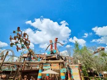 A wide view of the colorful How to Train Your Dragon – Isle of Berk land at Universal Epic Universe, featuring the towering Dragon Racer's Rally ride structure against a bright blue sky.