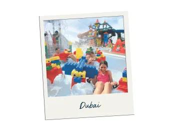 Kids on rubber rings with Lego building blocks on it and a huge water tower behind with water splashing down.