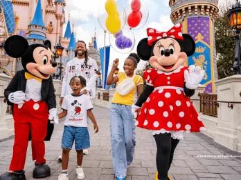 Mickey Mouse, Minnie Mouse, and a family walking in front of a Disney castle