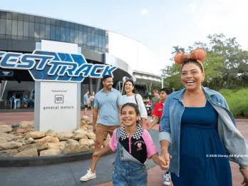 A happy family laughing together while walking past the Test Track attraction at EPCOT, Walt Disney World in Florida