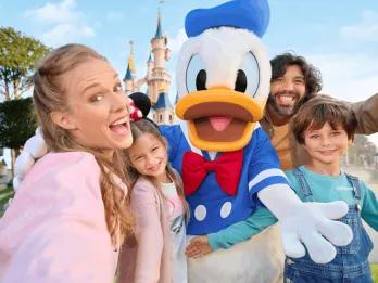 A happy family meeting Donald Duck at Disneyland Paris with the iconic castle in the background.