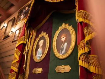 Royal portraits on the wall of Elsa and Anna and other paintings.