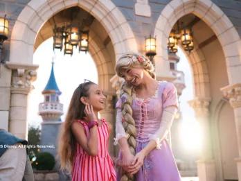 A young girl meeting Rapunzel in front of the castle at Disney World