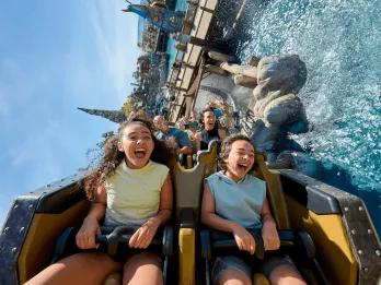 Riders laughing and screaming as their coaster splashes through water on Hiccup's Wing Gliders, Isle of Berk