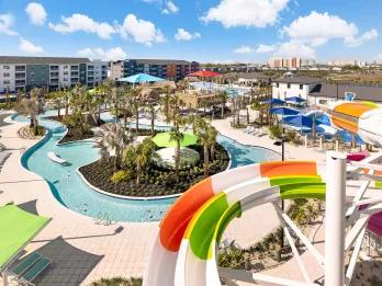 Elevated view of a winding lazy river pool surrounded by palm trees and resort buildings