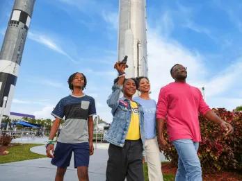A family walking past large rockets at the Kennedy Space Center Rocket Garden