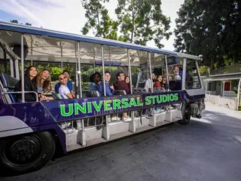 Guests smiling and waving from the Universal Studios electric tram during the studio tour