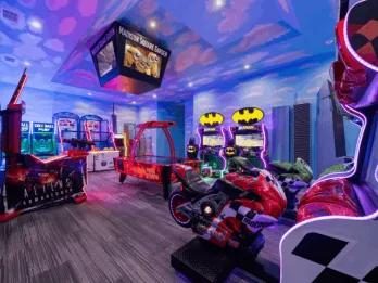 Indoor arcade game room with various arcade machines and New York skyline decorations