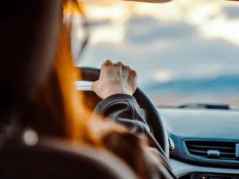 Over-the-shoulder view of a person holding a steering wheel while driving