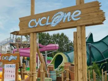 Entrance archway sign for the Cyclone water coaster at Caribe Aquatic Park with colorful water slides in the background