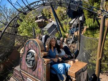 Two women smiling while riding the Curse of the Werewolf roller coaster