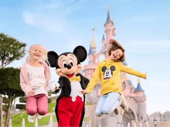Children jumping with Mickey Mouse in front of a castle at Disneyland Paris