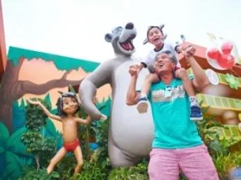 Father and son smiling while next to Jungle Book character statues