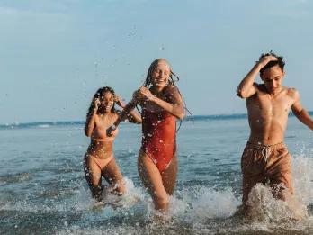 Three friends laughing and splashing in the sea on a summer holiday.