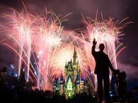 Happily Ever After Cinderella Castle lit up with fireworks in the background and a statue of Walt and Mickey in the foreground