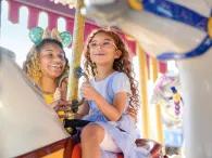 Prince Charming Regal Carrousel A girl and her mother riding a traditional carrousel