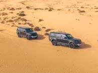 Two Land Rover Defenders driving through the Dubai desert