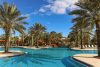 Communal pool with water slide and surrounded by palm trees at Solterra Resort