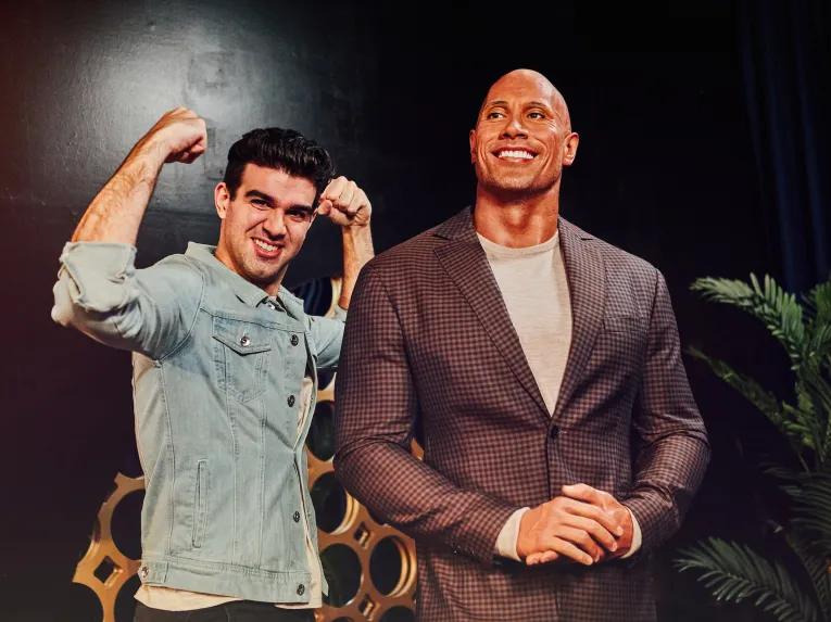 Guest posing with Dwayne Johnson at Madame Tussauds London