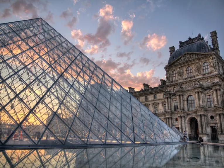 The glass pyramid of The Louvre museum in front of a sunset