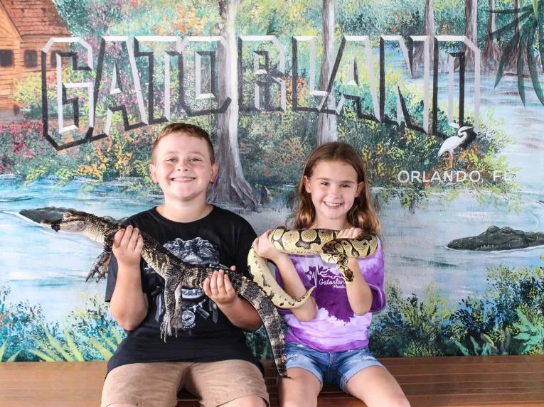 Boy holding a baby alligator and girl holding a snake at Gatorland