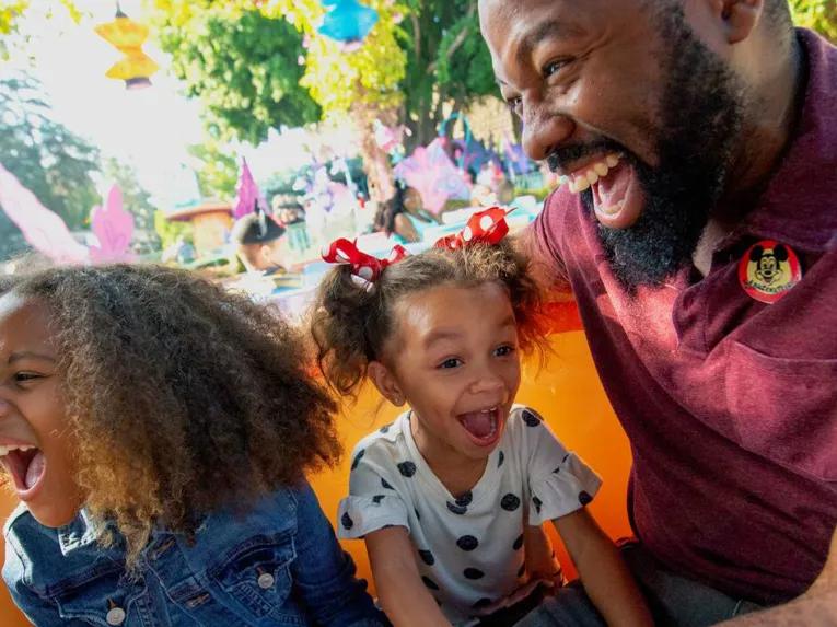 father and daughters enjoying a ride at Disneyland in California