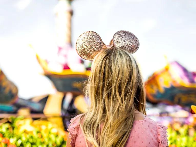 Girl with gold Disney ears in front of Magic Carpets of Aladdin, Walt Disney World