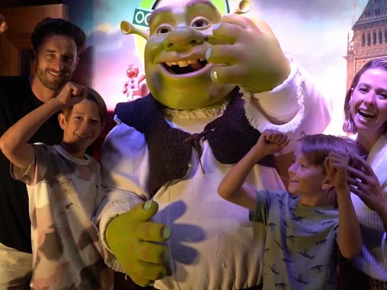 Eine lachende Familie steht mit der Filmfigur Shrek in Shrek's Adventure