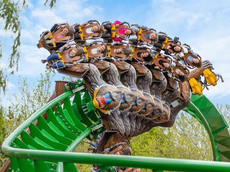 Monkey shaped rollercoaster cart twisting around a turn on the green rollercoaster track.