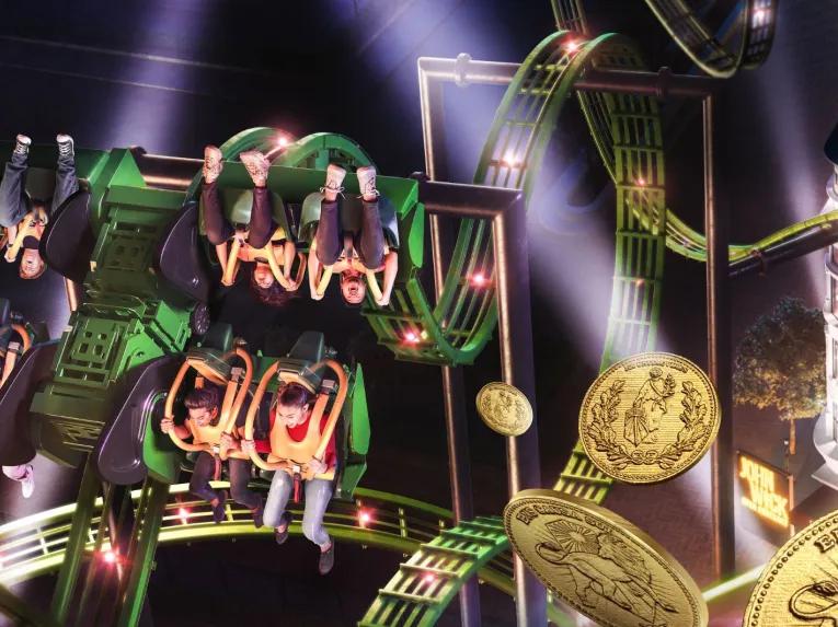 John Wick: Open Contract roller coaster at MOTIONGATE™ Dubai with riders upside down, glowing loops and a dramatic nighttime setting