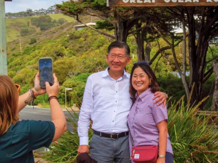 Two smiling tourists posing for a photo at the iconic Memorial Arch