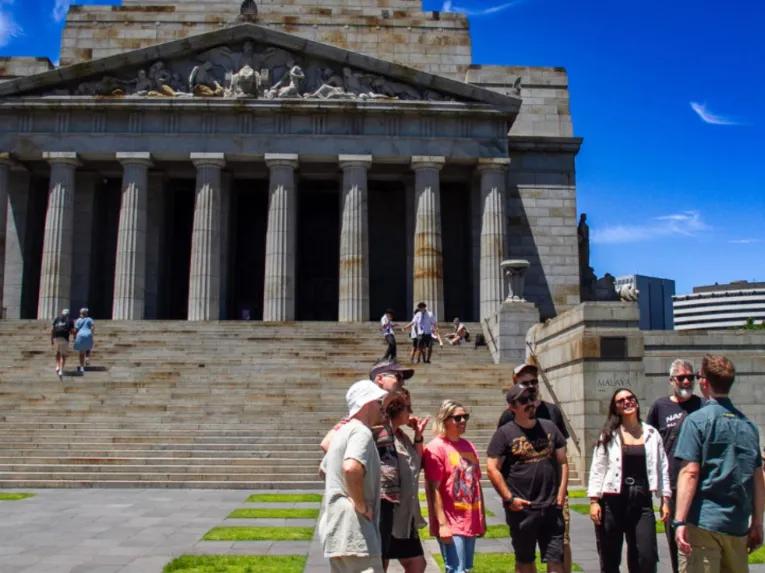Tour group smiling and standing outside the Shrine of Remembrance during the Melbourne City Discovery Tour