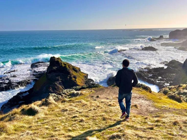 Person standing on a cliff edge at the Nobbies, overlooking stunning ocean and coastal scenery