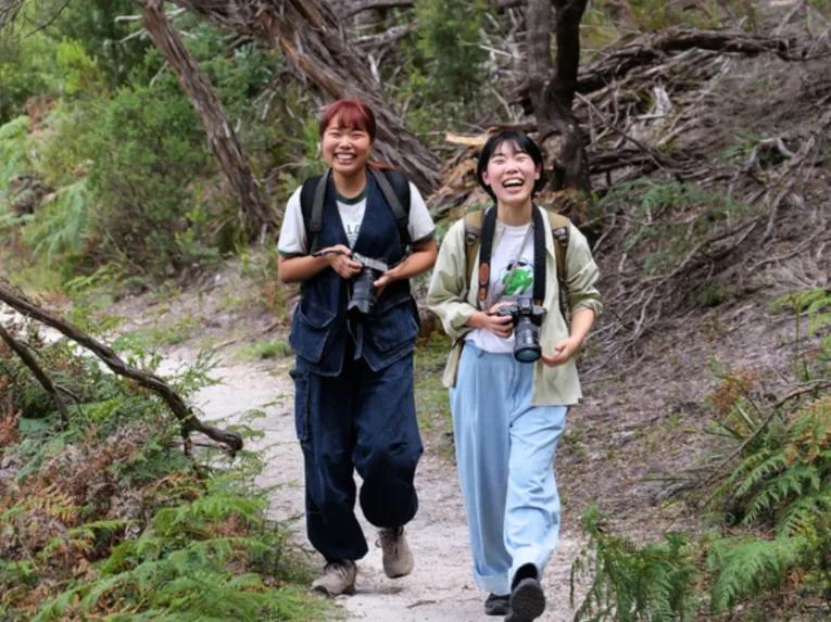 Two happy people walking through lush woodlands on a guided hike at Wilsons Promontory