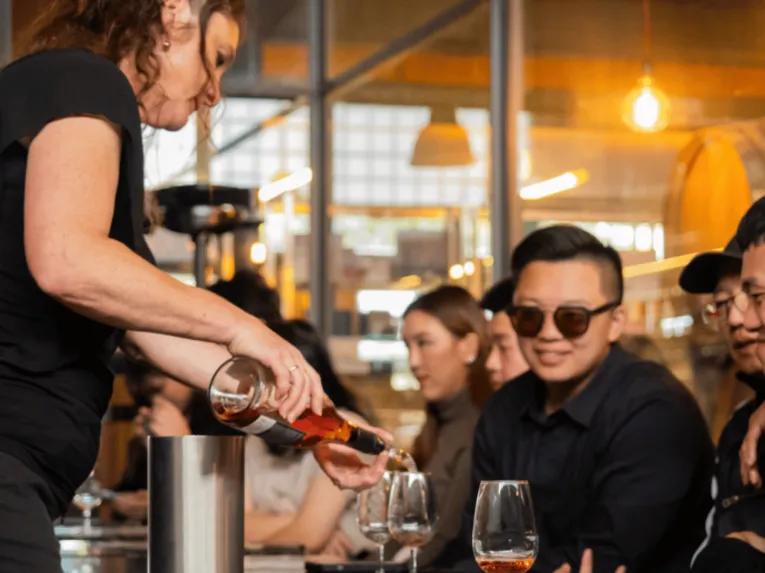 Lady pouring wine for smiling people on the Yarra Valley Grazing Tour