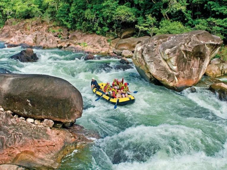 A raft full of people paddling through the Tully River